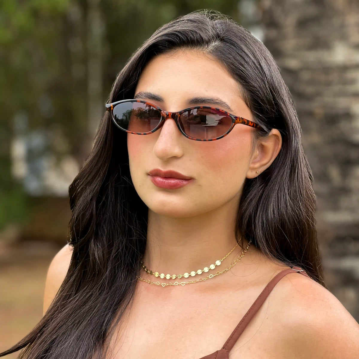 Mulher usando óculos de sol feminino Razzi Brasil com armação em acetato tartaruga e lentes escuras.